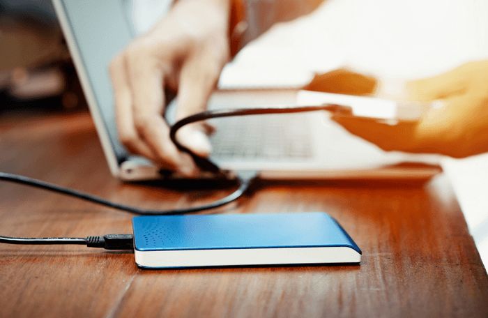 Illustratie van een persoon die een externe harde schijf aansluit op een laptop