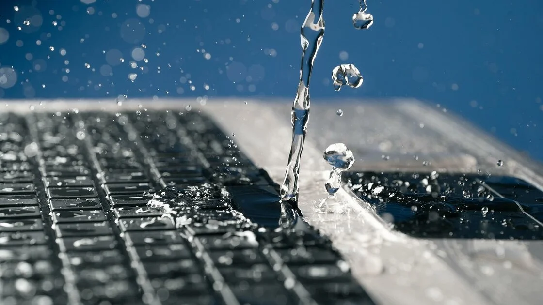 water dat over het toetsenbord van laptop wordt gegoten